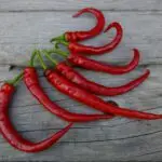 Mature Aci Ilica 256 hot pepper pods photographed on a wooden surface.