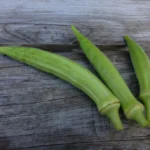 Three Yalova Akkoy okra pods photographed on an old wooden cabinet.