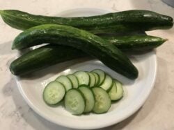 Sliced and whole Kelahmet Long cucumbers displayed in a white plate