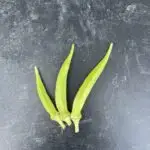 Three Bayramiç White okra pods photographed on backdrop with granite pattern.