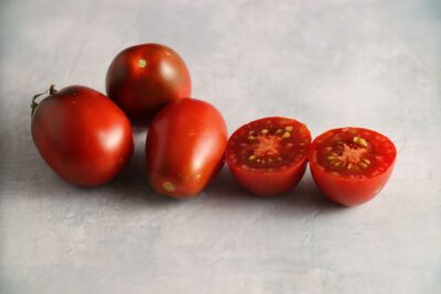 Black Plum2 Three whole and one half Black Plum tomato fruits photographed on backdrop with marble pattern.