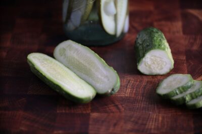 Boston Pickling2 Sliced and halved Boston Pickling cucumber fruits photographed on a backdrop with wood texture.