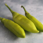 Three Pestişori Ciorbagiu peppers photographed on photography backdrop with concrete texture.