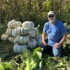 Man with stacked Adapazari white pumpkins outdoors
